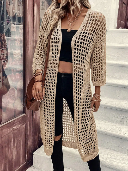 Person wearing a beige crochet cardigan with a blurred background