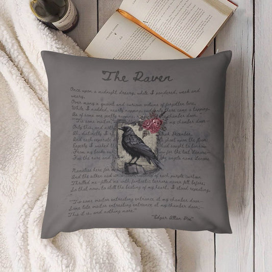 Gray pillow with 'The Raven' poem and a crow illustration on a wooden surface.