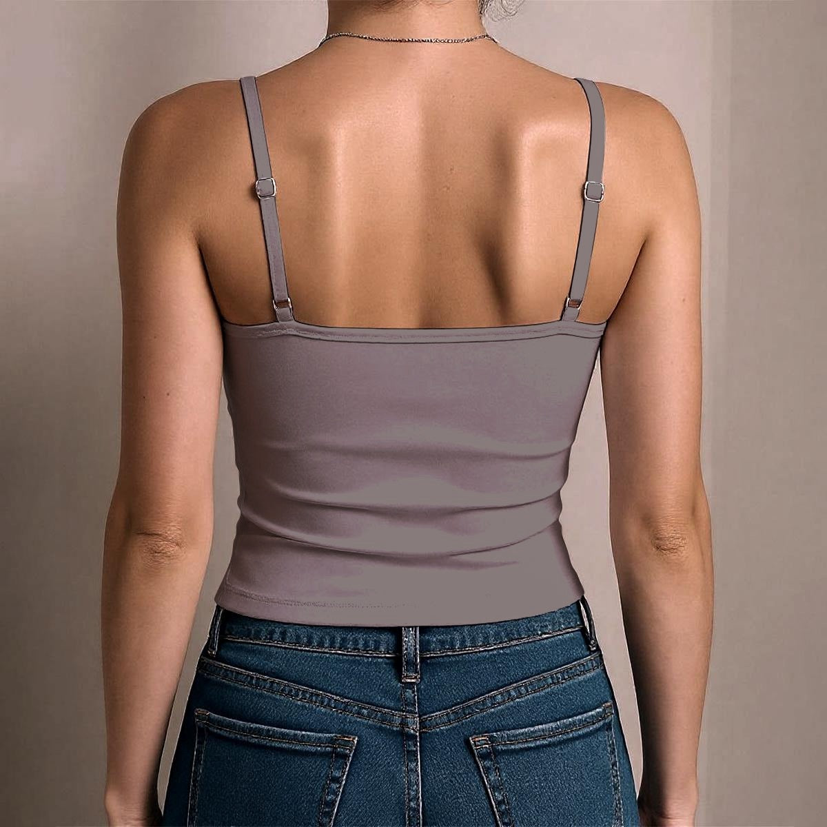 Person wearing a gray tank top and blue jeans against a beige background