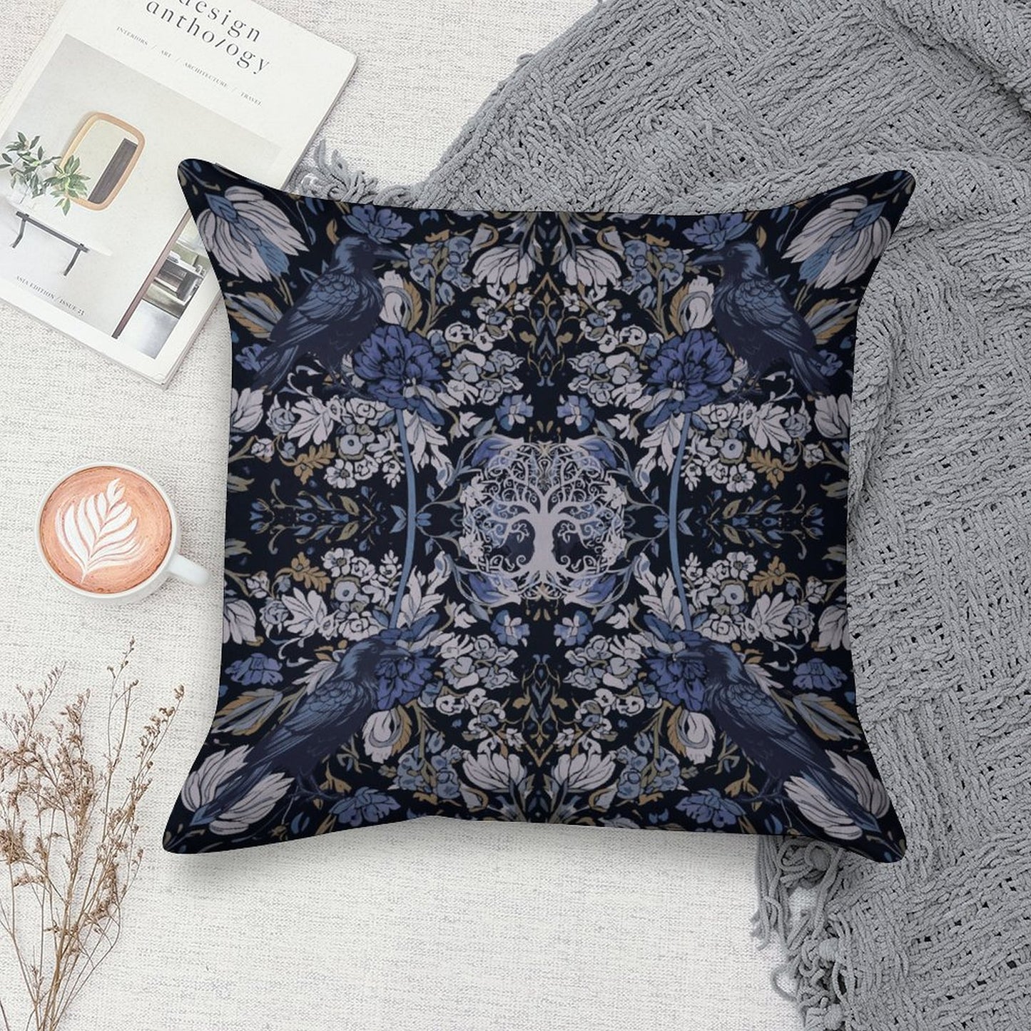 Decorative pillow with floral and bird pattern on a surface with a book and cup of coffee.