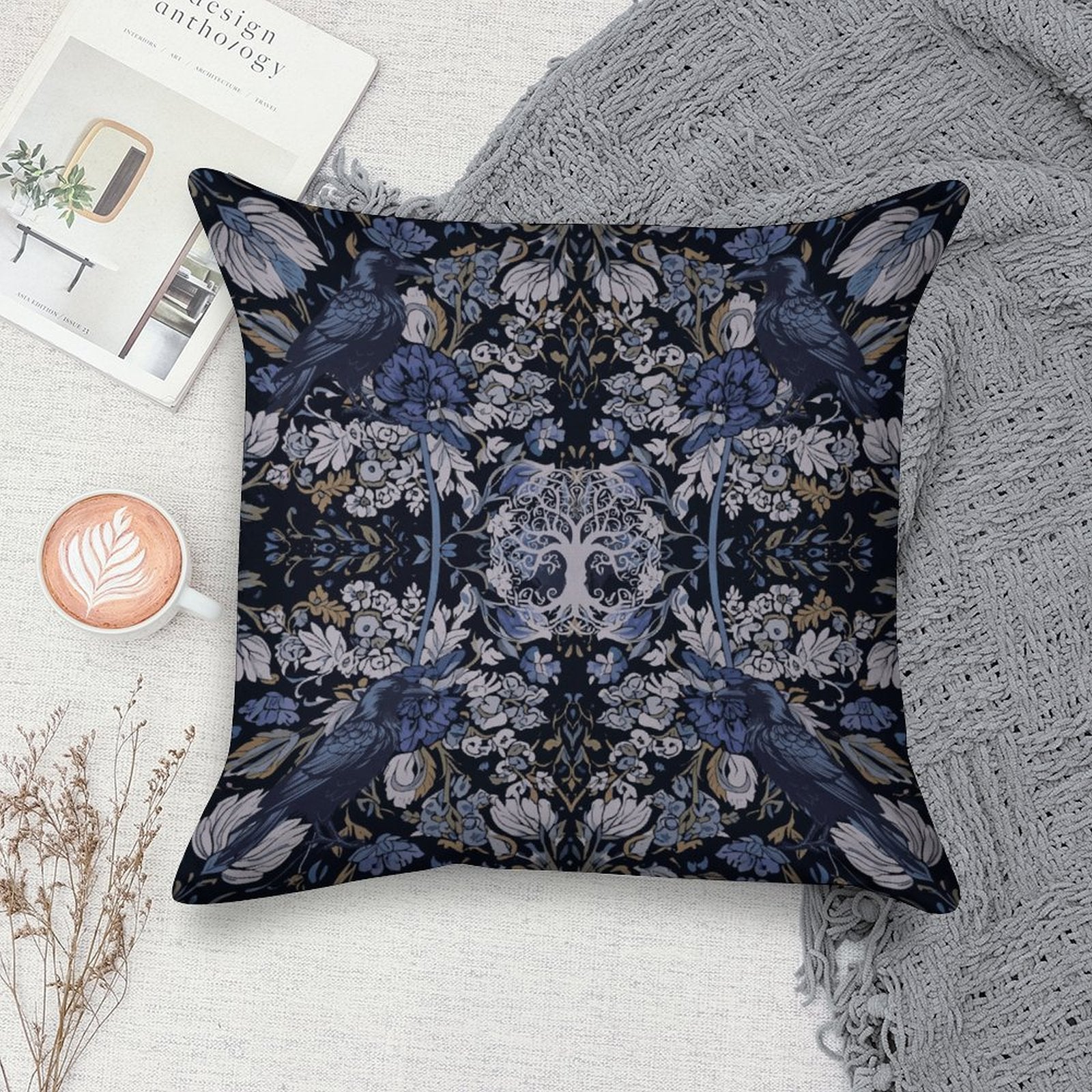 Decorative pillow with floral and bird pattern on a surface with a book and cup of coffee.