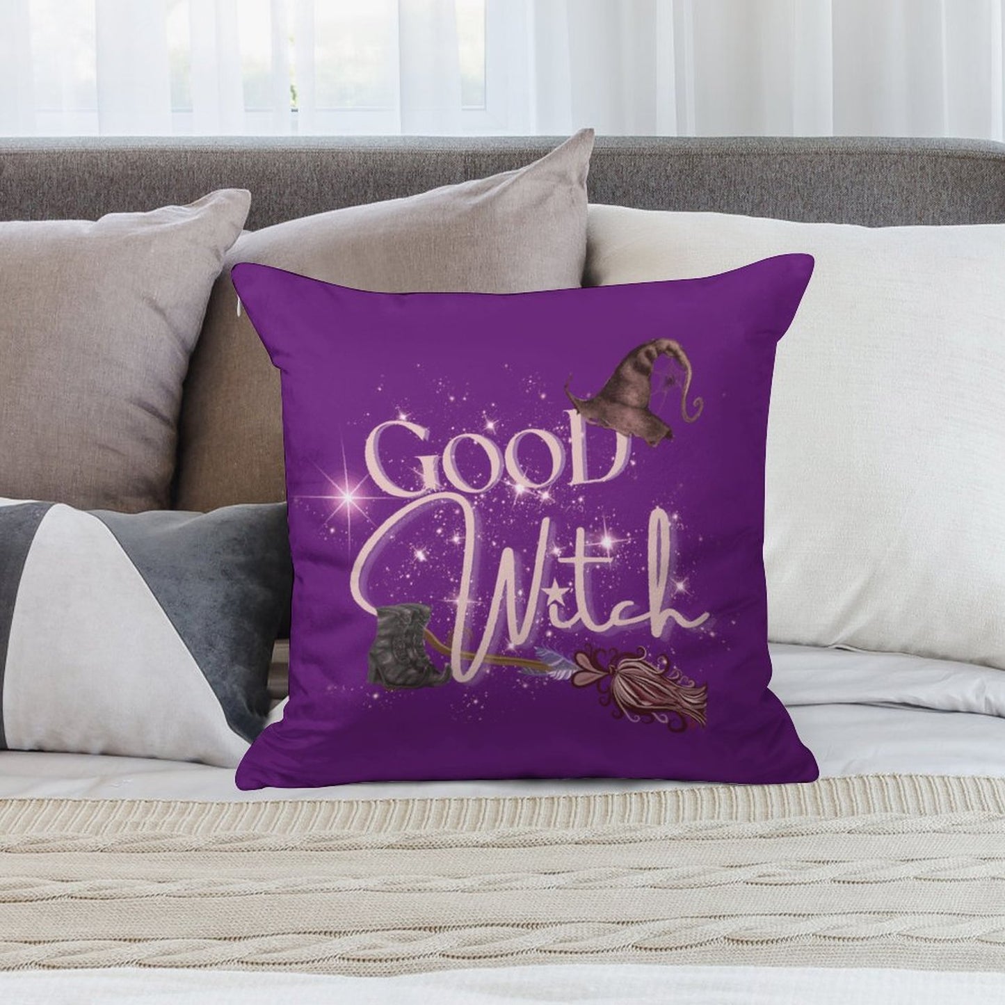 Purple pillow with 'Good Witch' text and witch hat design on a couch.