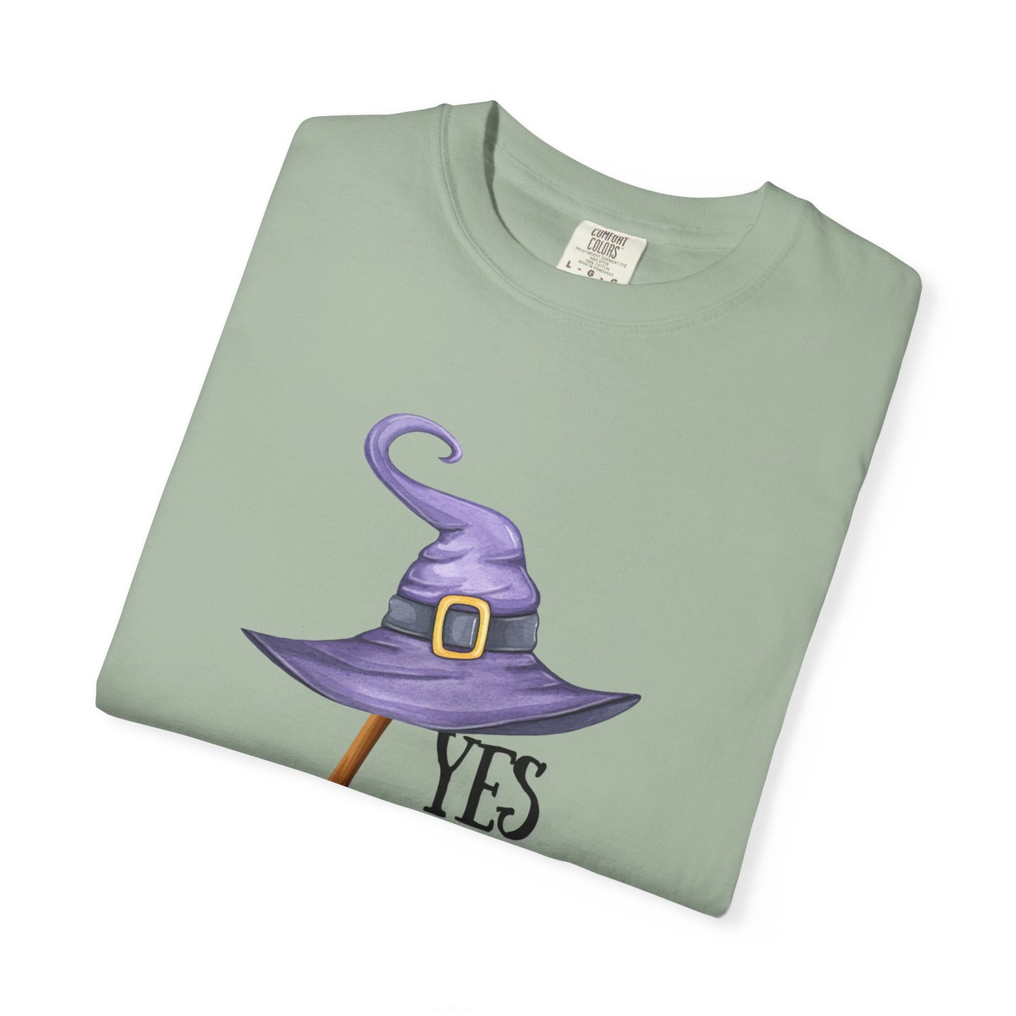 Folded green t-shirt with a purple witch hat graphic and 'YES' text on a white background