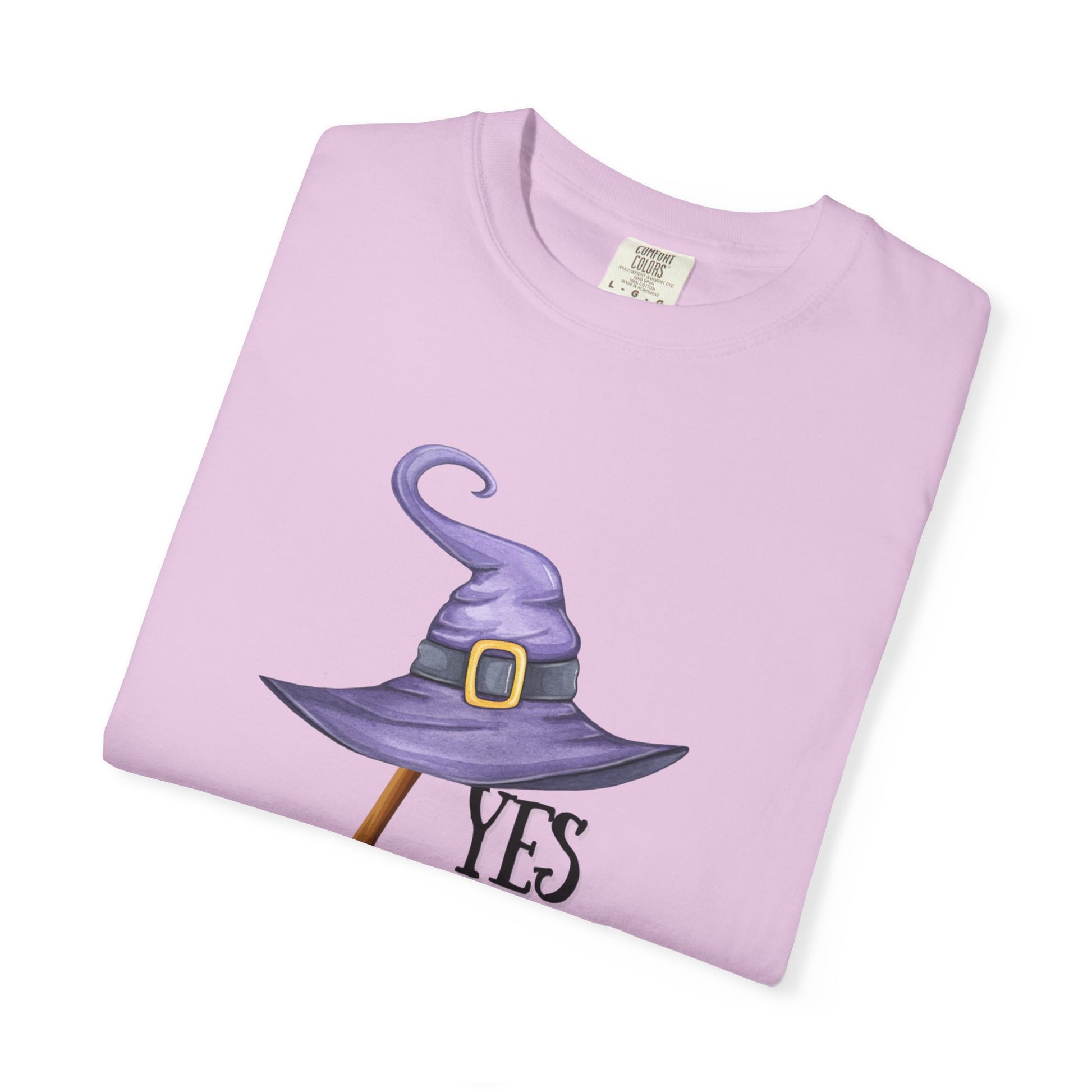 Folded pink t-shirt with a witch hat graphic and 'YES' text on a white background