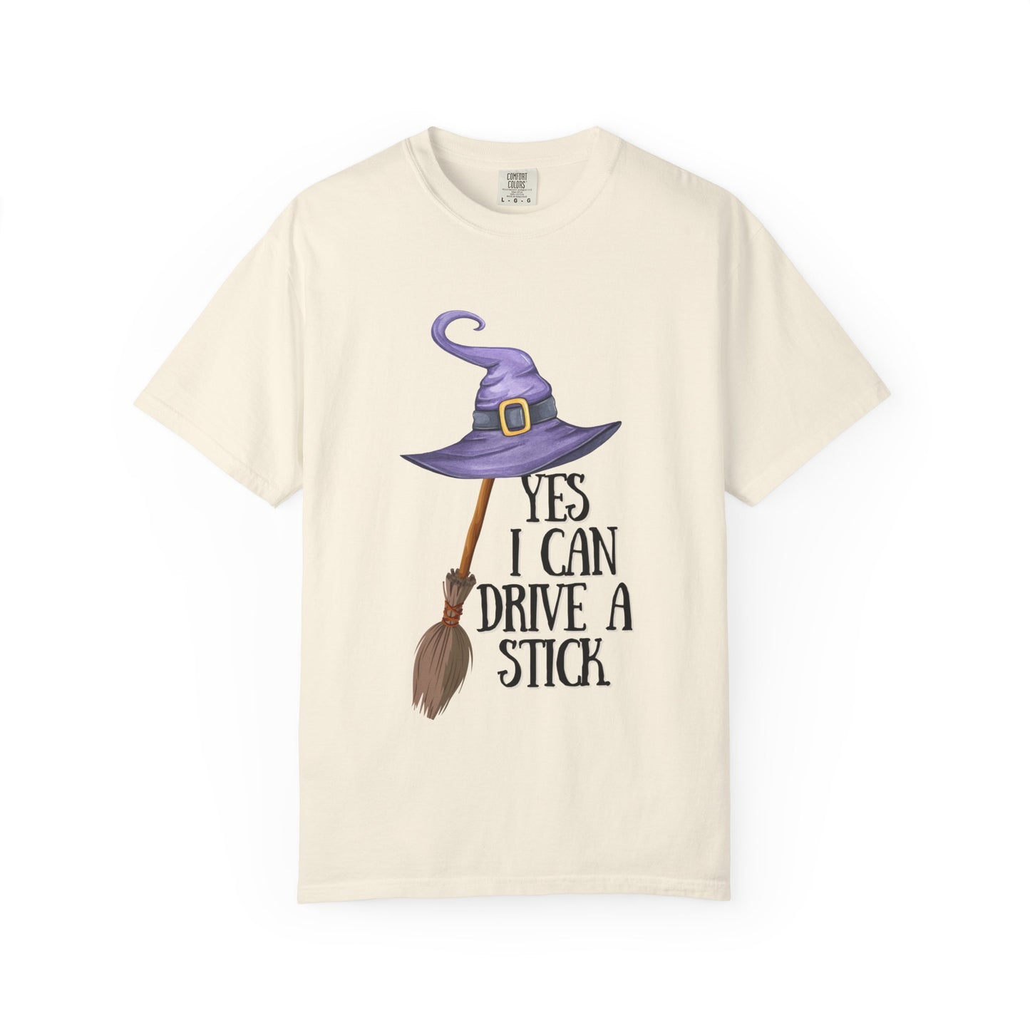 Beige t-shirt with witch hat, broom, and text design on a white background