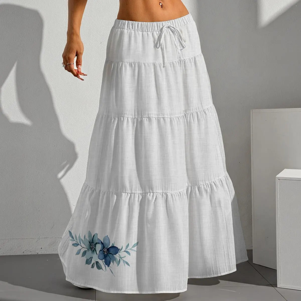 White tiered skirt with floral embroidery on a plain background
