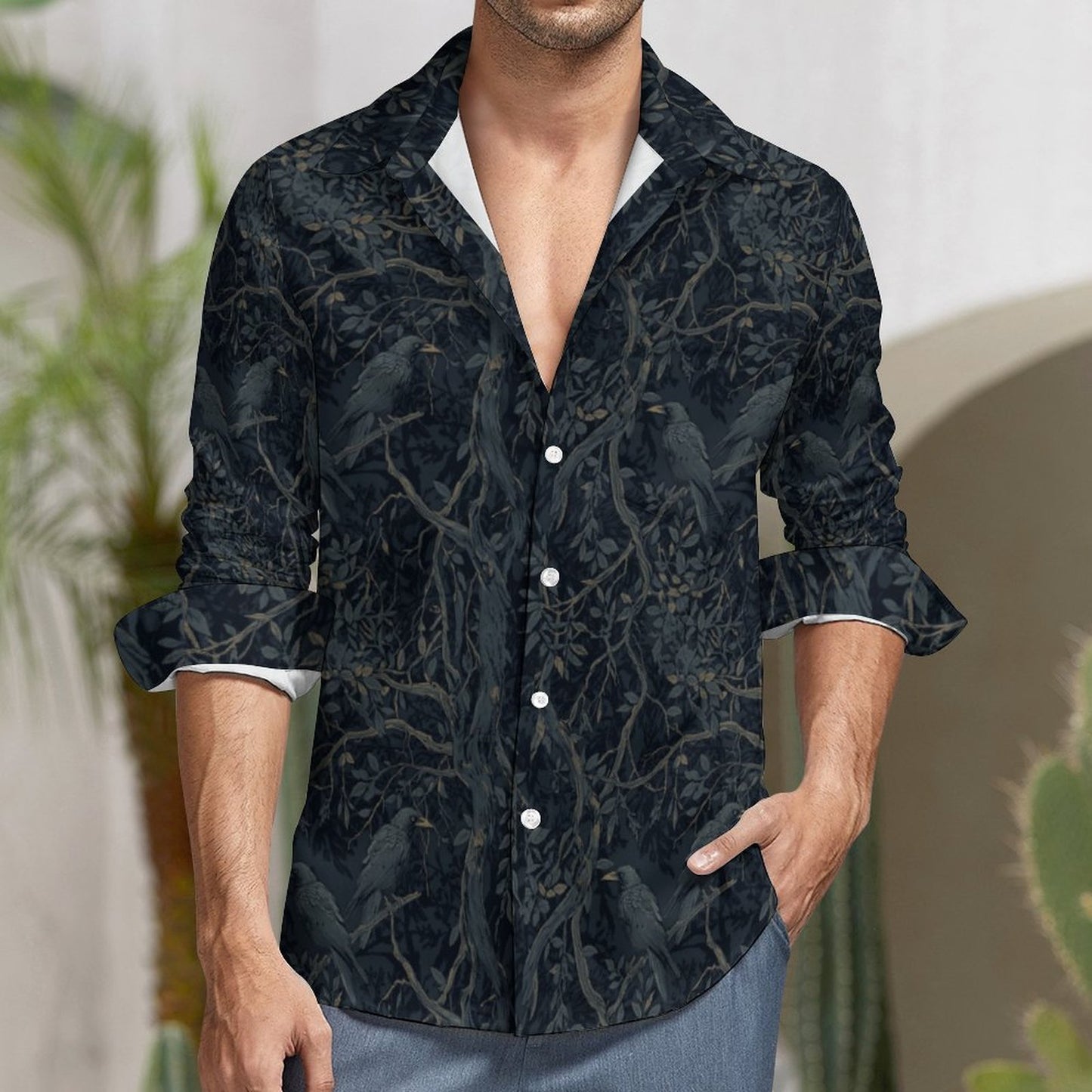 Man wearing a dark patterned shirt with rolled-up sleeves in an outdoor setting