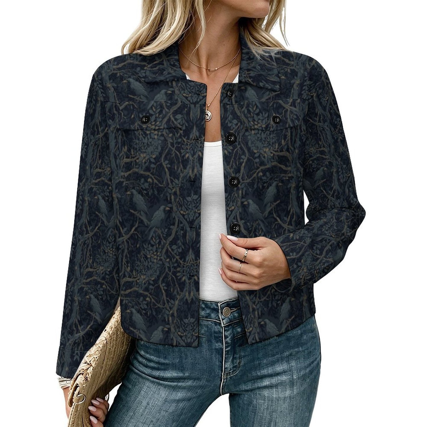 A woman wearing a dark patterned button-up jacket with a subtle bird and branch print, styled over a white top and blue jeans against a plain white background.