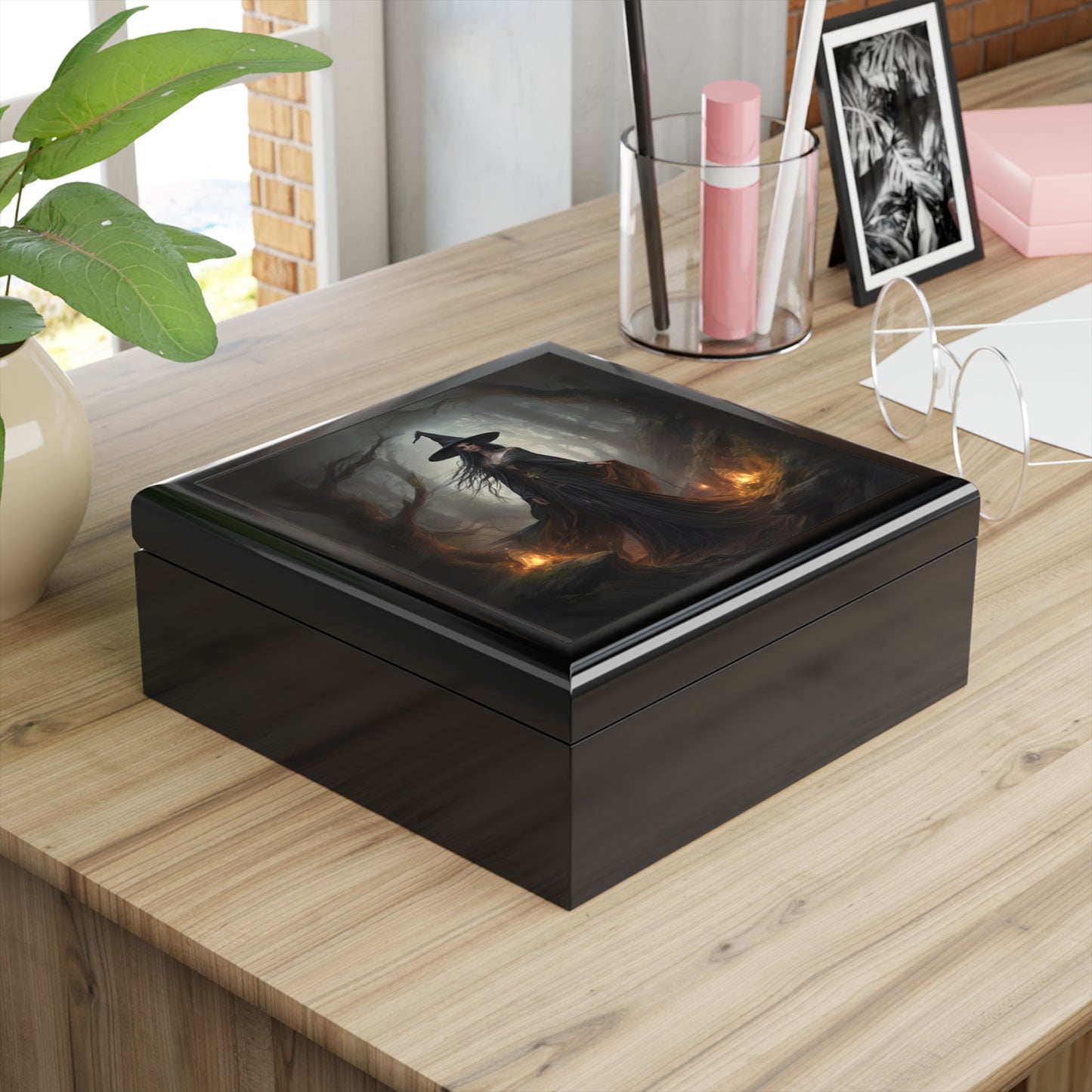 Black decorative box on a wooden surface with a plant and other items in the background