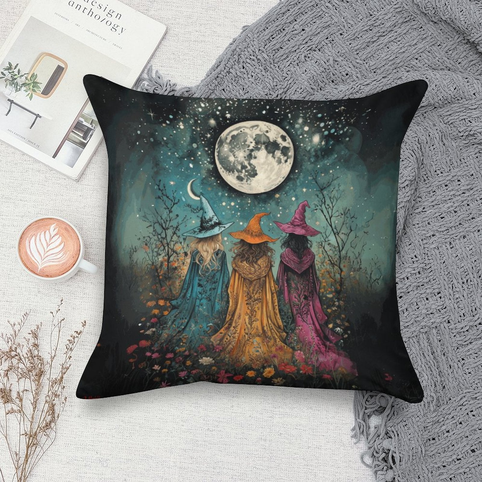 Decorative pillow with three witches under a moonlit sky on a textured surface.