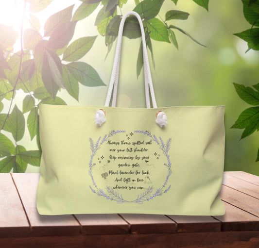 Light green tote bag with text and floral design on a wooden surface with a leafy background