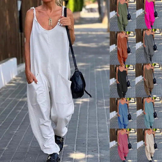 Woman in a white sleeveless jumpsuit walking on a sidewalk with a black bag.